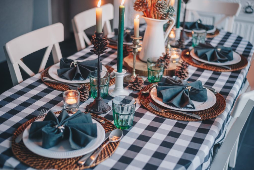 Healthier takes on traditional Christmas foods keep weight down. Holiday table setting with green linens and burning candles.